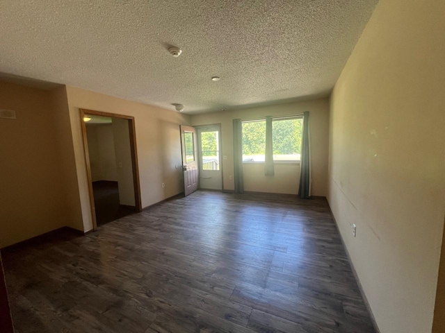 empty room featuring a textured ceiling and dark hardwood / wood-style floors