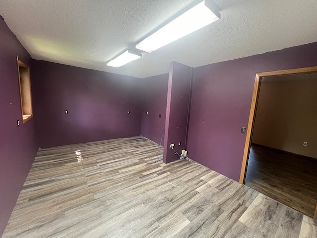 unfurnished room with a textured ceiling and light hardwood / wood-style flooring