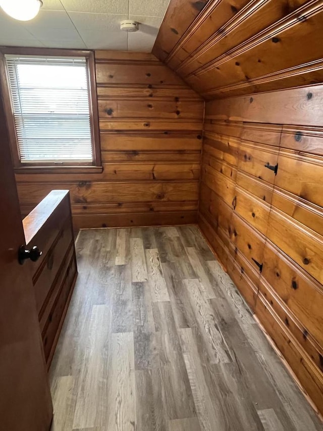 additional living space featuring hardwood / wood-style flooring, vaulted ceiling, and wooden walls