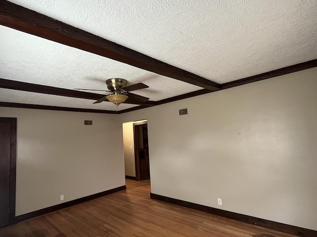 empty room featuring ceiling fan, dark hardwood / wood-style floors, a textured ceiling, and beam ceiling