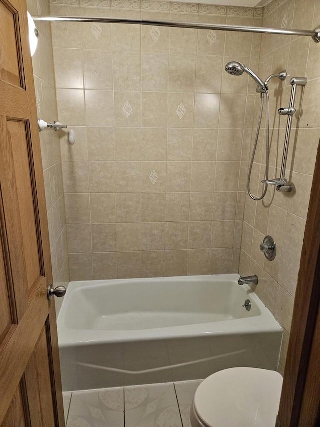 bathroom featuring tile patterned floors, tiled shower / bath combo, and toilet