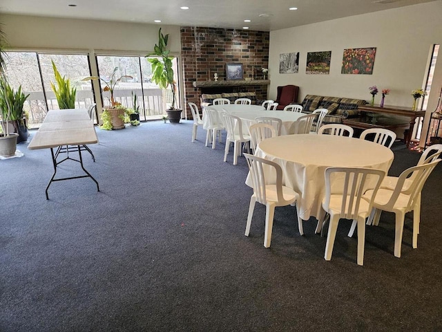 dining space with dark carpet and a brick fireplace