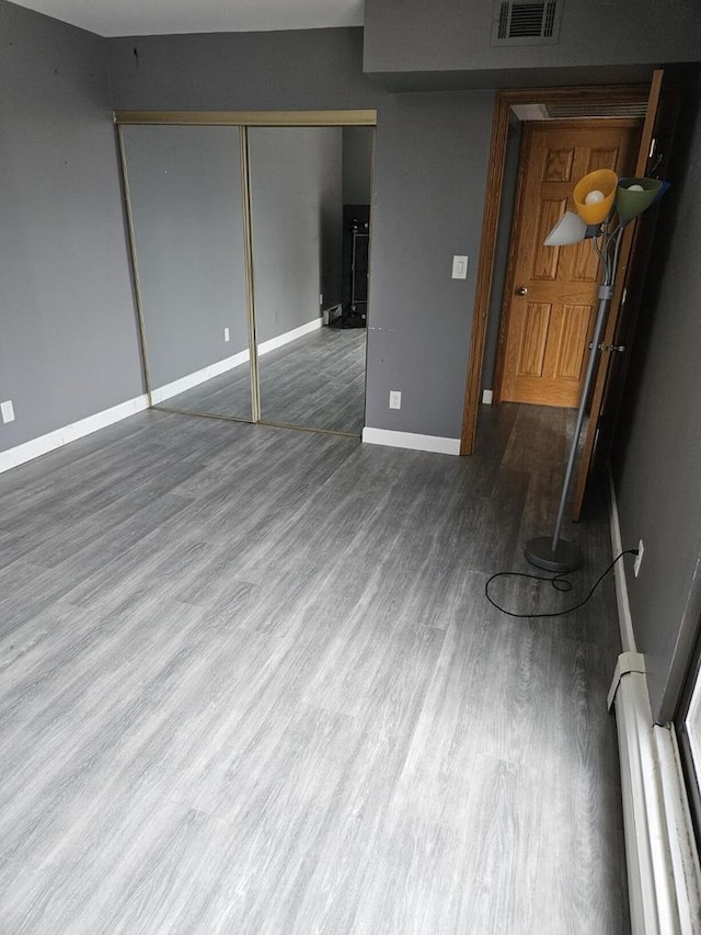 unfurnished living room with a baseboard radiator and hardwood / wood-style flooring