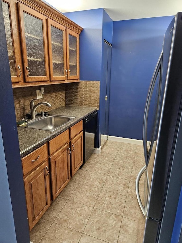 kitchen with tasteful backsplash, sink, light tile patterned floors, black dishwasher, and stainless steel refrigerator