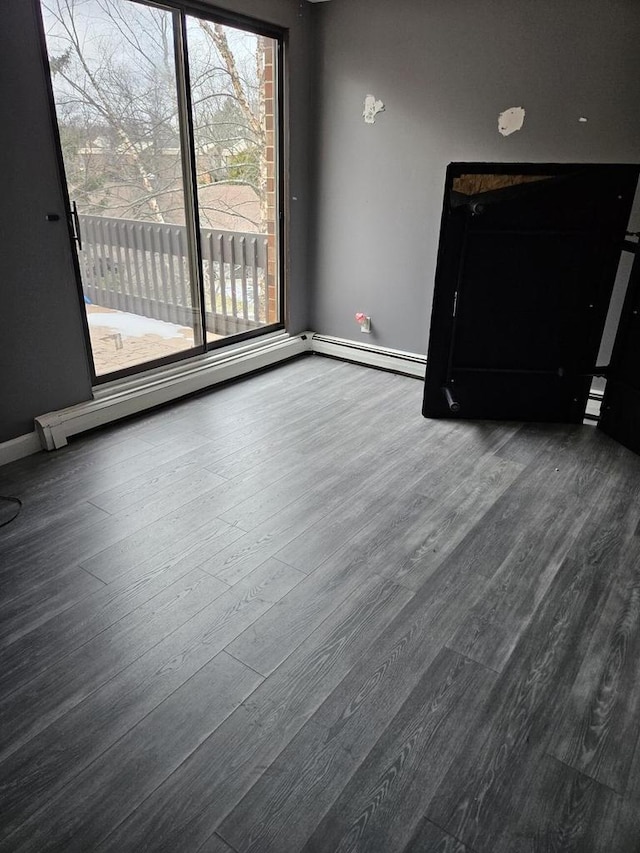 unfurnished living room featuring wood-type flooring and a baseboard heating unit