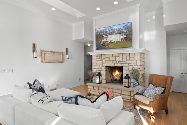 living room with a skylight, a fireplace, light wood-type flooring, and ornamental molding