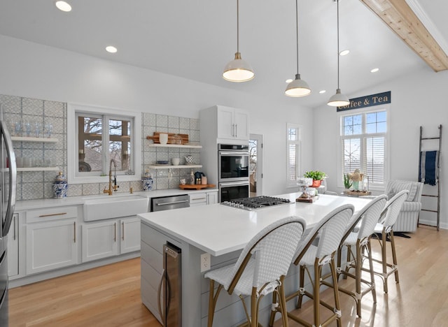 kitchen with stainless steel appliances, beverage cooler, sink, pendant lighting, and white cabinets