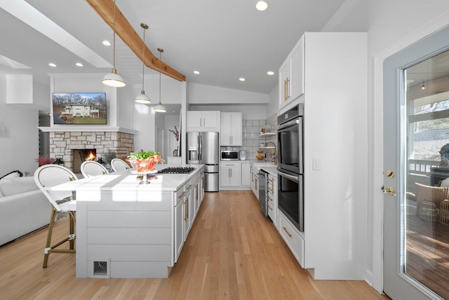 kitchen with white cabinetry, a center island, hanging light fixtures, and appliances with stainless steel finishes