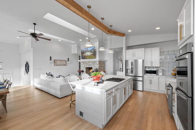 kitchen with a center island, stainless steel appliances, backsplash, pendant lighting, and white cabinets