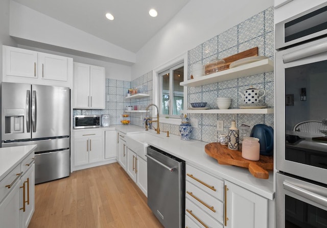 kitchen with white cabinets, sink, vaulted ceiling, tasteful backsplash, and stainless steel appliances