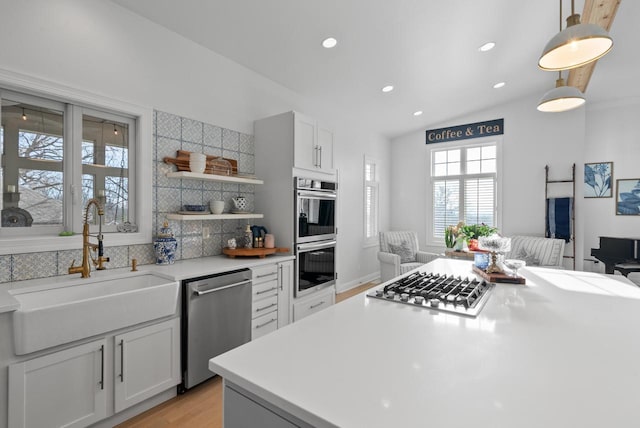 kitchen with white cabinets, decorative light fixtures, sink, and stainless steel appliances