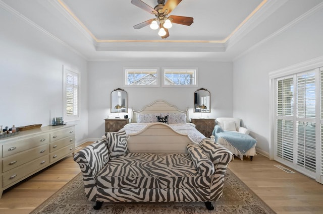 bedroom with a raised ceiling, ceiling fan, and light hardwood / wood-style floors