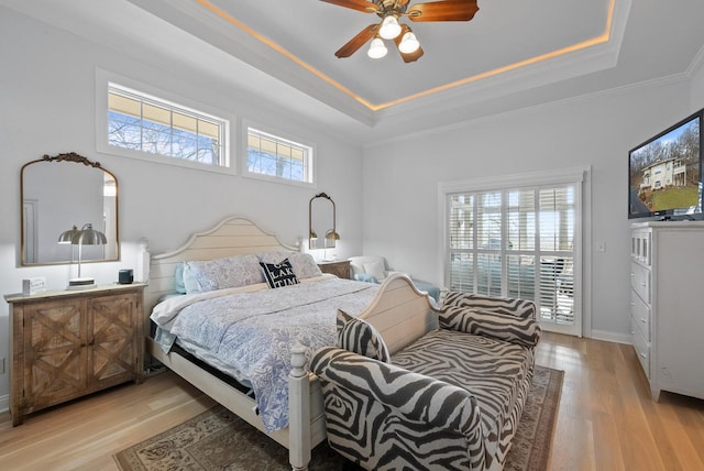 bedroom featuring light hardwood / wood-style floors, a raised ceiling, and ceiling fan