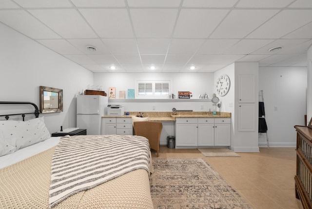 bedroom with white refrigerator and a paneled ceiling