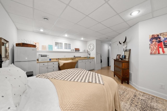 bedroom featuring white refrigerator and a paneled ceiling