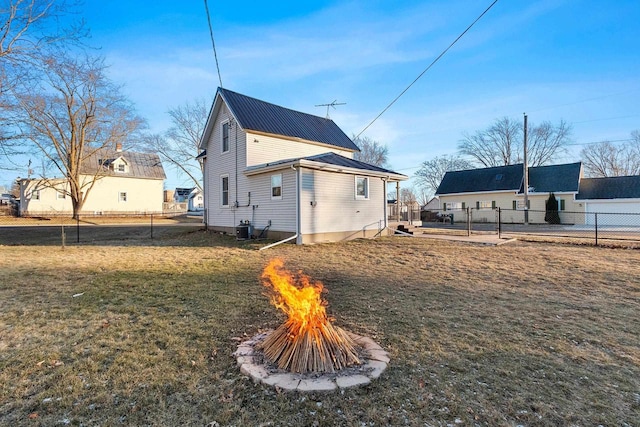 rear view of property featuring central air condition unit and a lawn