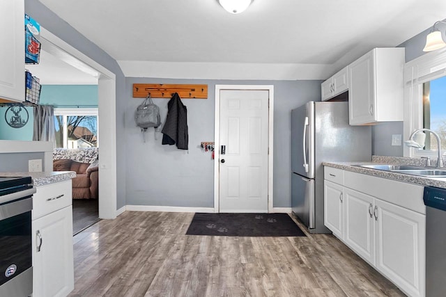 kitchen with sink, white cabinetry, stainless steel appliances, and light hardwood / wood-style flooring