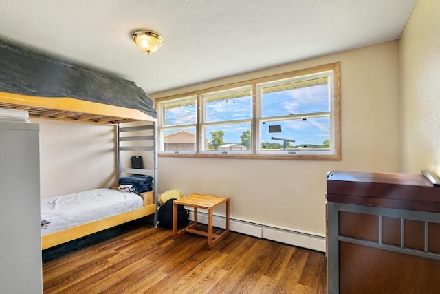 bedroom with hardwood / wood-style floors and a baseboard heating unit