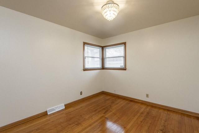 spare room featuring hardwood / wood-style floors and a notable chandelier