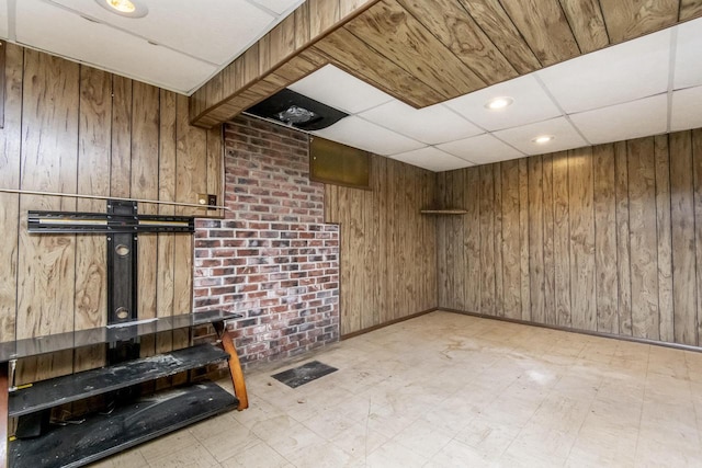 unfurnished living room with a paneled ceiling and wood walls