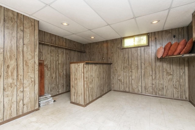 empty room with a drop ceiling and wood walls