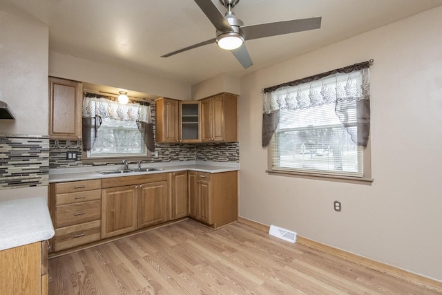 kitchen with tasteful backsplash, ceiling fan, sink, and light hardwood / wood-style flooring