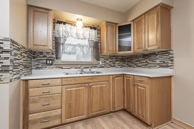 kitchen featuring decorative backsplash, light wood-type flooring, and sink