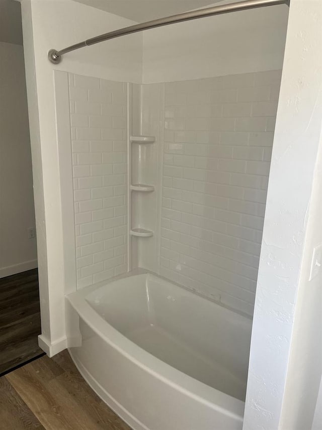 bathroom with washtub / shower combination and wood-type flooring