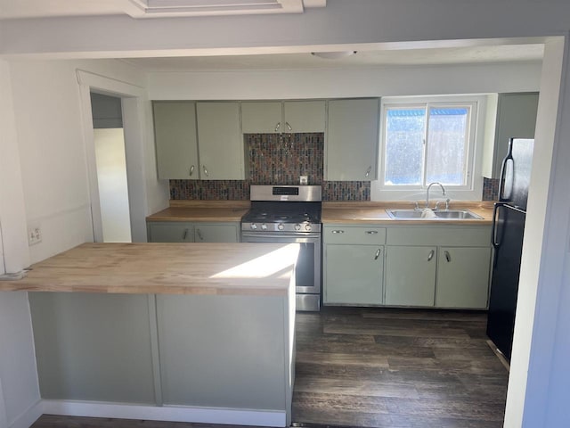 kitchen featuring wood counters, backsplash, black refrigerator, sink, and stainless steel range