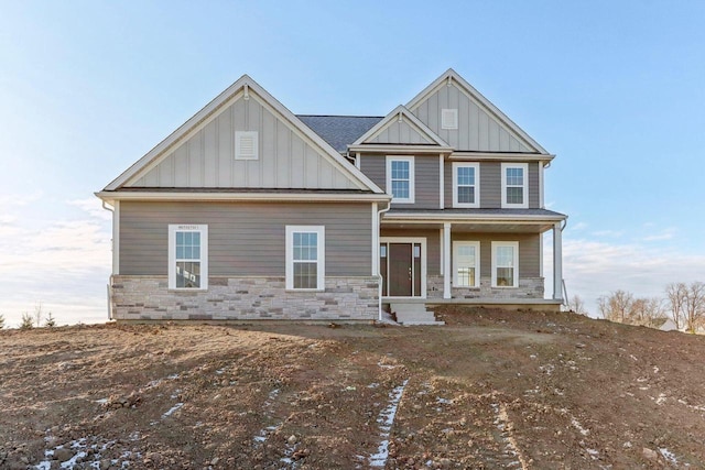 craftsman house with board and batten siding, covered porch, and stone siding
