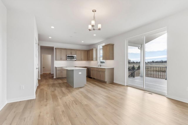 kitchen with sink, decorative light fixtures, a chandelier, light hardwood / wood-style floors, and a kitchen island