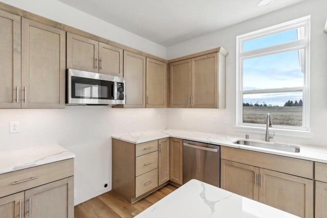 kitchen featuring a healthy amount of sunlight, sink, stainless steel appliances, and light wood-type flooring