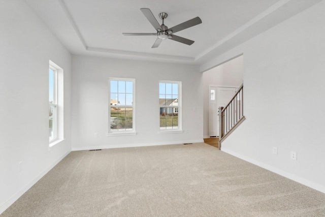 unfurnished living room with carpet, ceiling fan, and a tray ceiling