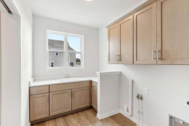 washroom featuring cabinets, light hardwood / wood-style floors, hookup for an electric dryer, and sink