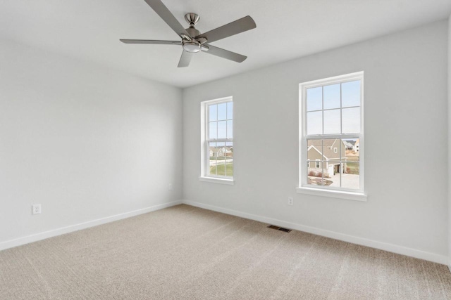 carpeted empty room with ceiling fan and a healthy amount of sunlight