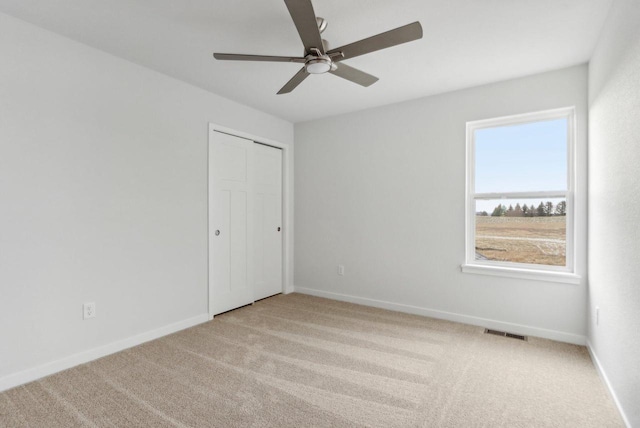 unfurnished bedroom with light carpet, a closet, and ceiling fan