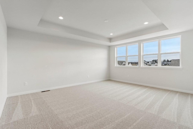 carpeted spare room with a tray ceiling