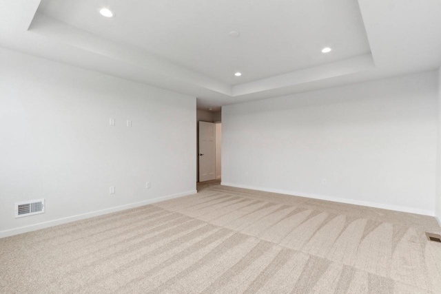 unfurnished room with a tray ceiling and light colored carpet