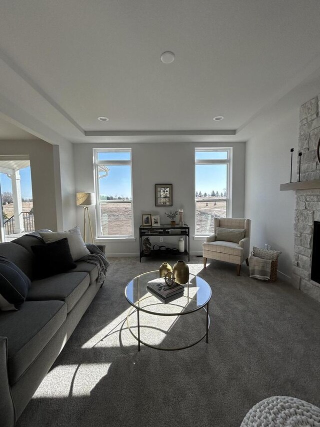 living room with carpet flooring, a stone fireplace, and plenty of natural light