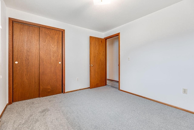 unfurnished bedroom featuring light carpet and a closet