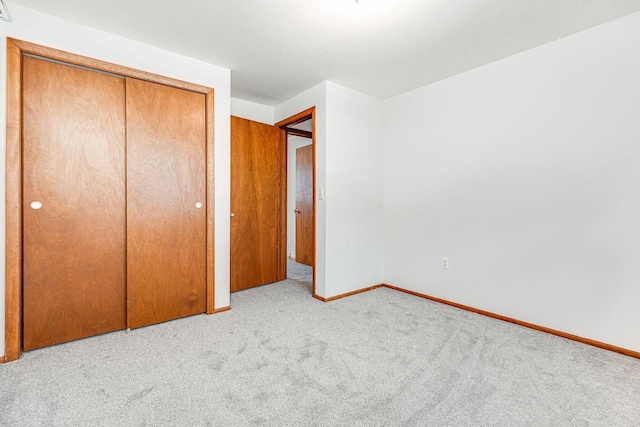 unfurnished bedroom featuring light colored carpet and a closet