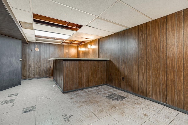 bar featuring a drop ceiling, dark brown cabinets, and wooden walls