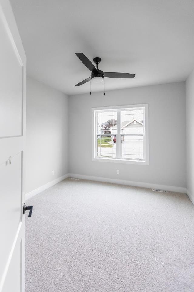 carpeted spare room featuring ceiling fan