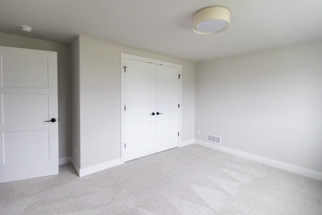 unfurnished bedroom with a closet and light colored carpet