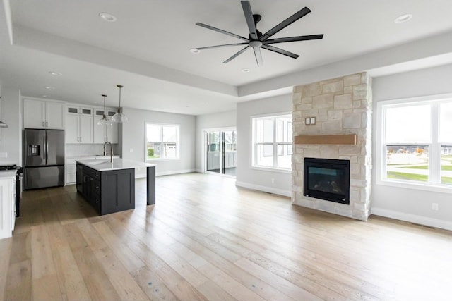 kitchen with pendant lighting, a kitchen island with sink, white cabinets, ceiling fan, and stainless steel fridge with ice dispenser