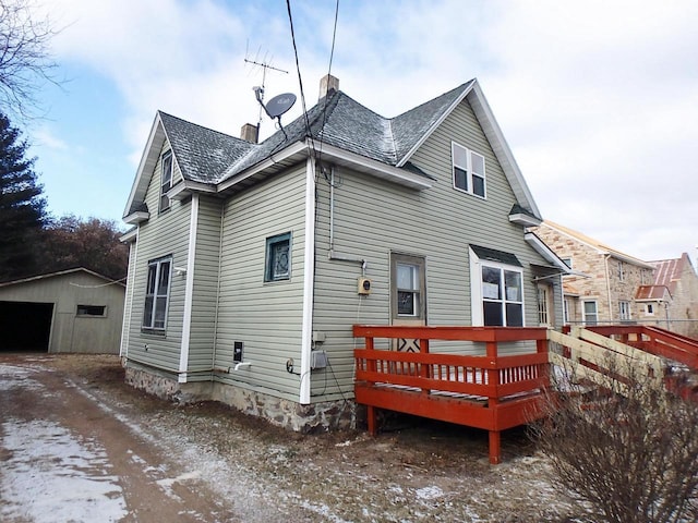 back of property featuring an outbuilding and a deck