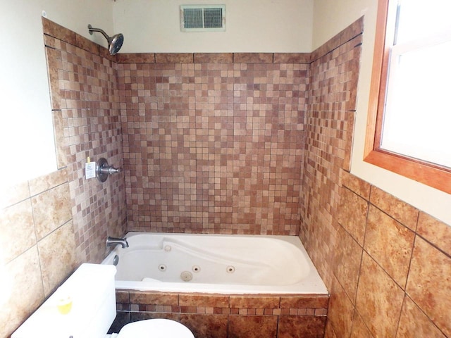 bathroom featuring toilet and tiled shower / bath