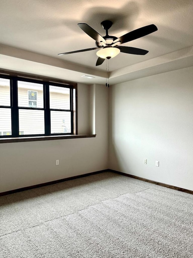 empty room featuring carpet flooring, ceiling fan, and a raised ceiling