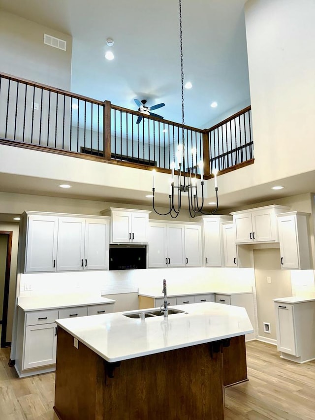 kitchen with a high ceiling, white cabinetry, ceiling fan, and sink