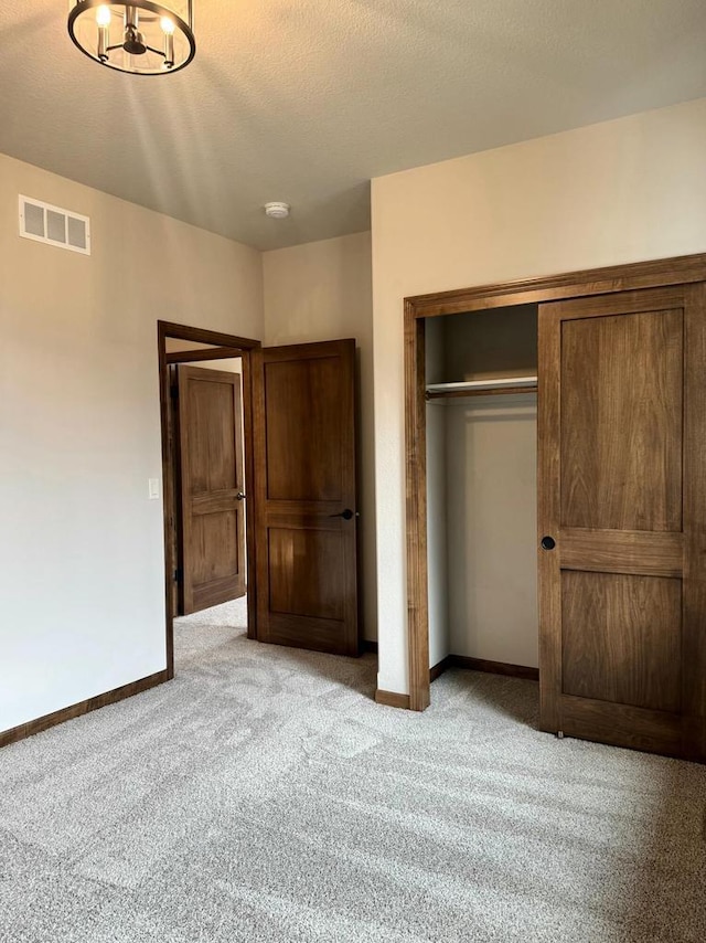 unfurnished bedroom featuring light colored carpet, a textured ceiling, and a closet